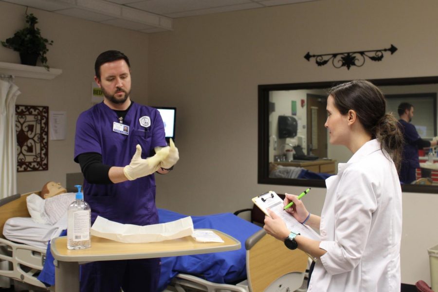 ACC nursing student Ross Fraser demonstrates how to correctly apply sterile gloves as instructor Stephanie Armstrong observes on Feb. 10, 2018, in Littleton, Colo. ACC and other community colleges could offer bachelors degrees in nursing if House Bill 1086 becomes law.