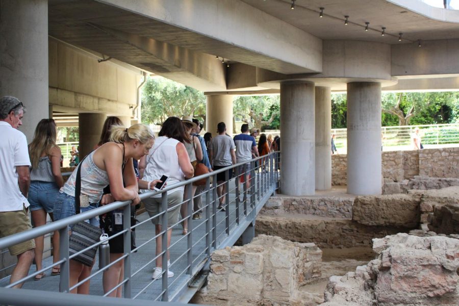 Groups of people walk around the ruins.  The railing protects both the visitors and the excavation site. Photo taken on Monday, June 24, 2019.