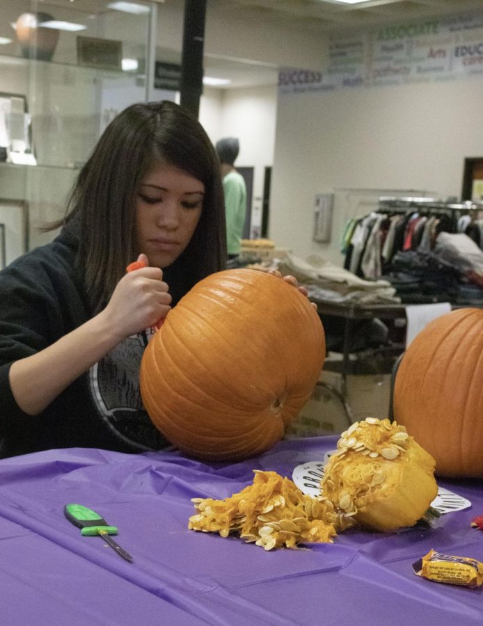 ACC student carving out the fibrous strands and seeds of her pumpkin on Thursday, Oct 24 2019. 