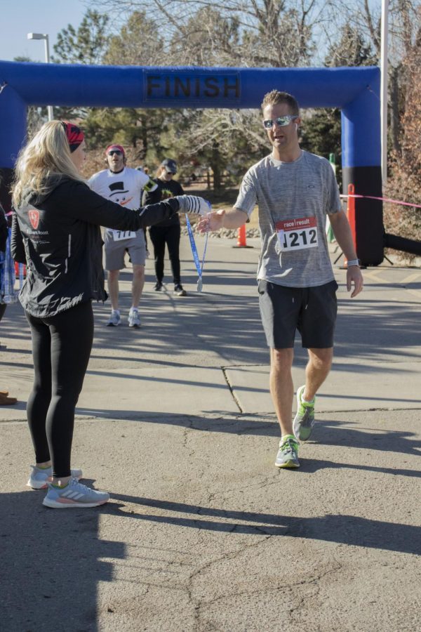 Volunteer at the Frostys Frozen five and 10 mile handing out medals to all runners who pass the finish line on Saturday, January 25, 2020.