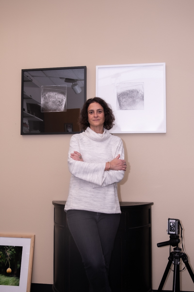 The Art & Design Center's Program Chair Angela Faris Belt Standing in her office in front of her artworks.