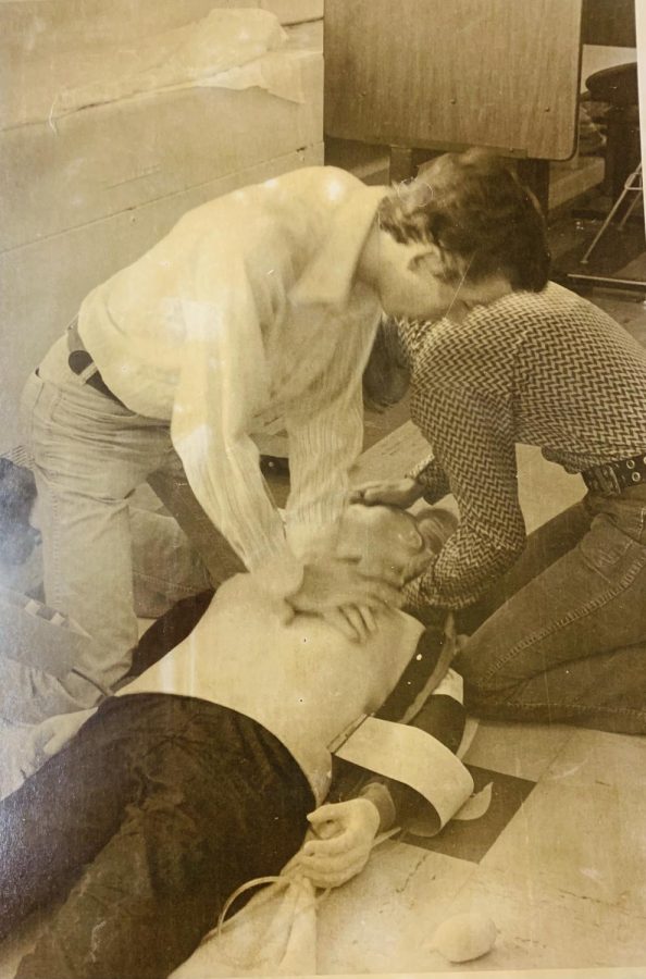 Two students from around 1970 presumably practicing CPR on a test dummy. 