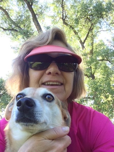 A picture of ACC Professor Diana Hornick in a pink shirt and visor with her white dog, Monty.