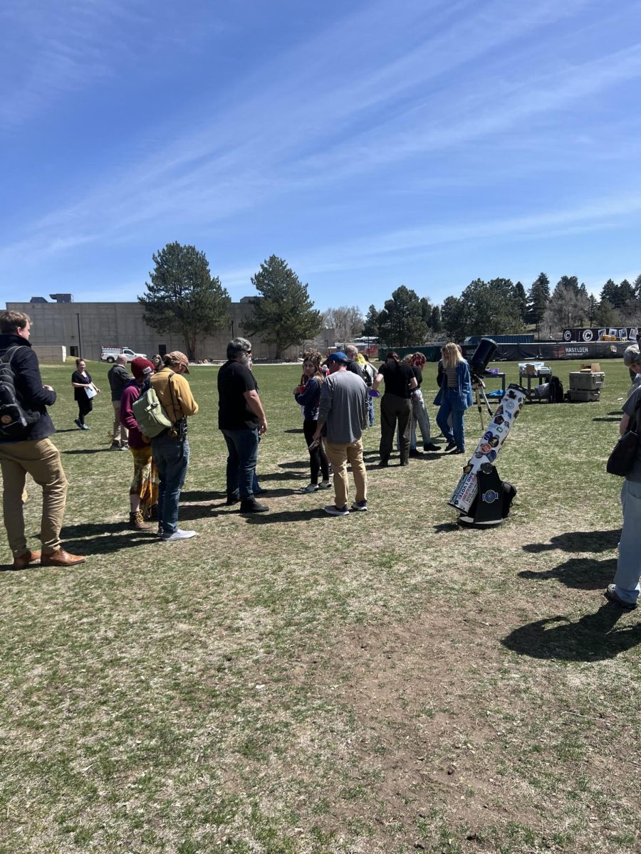People gather wait in line to look at the eclipse through a telescope at Arapahoe Community College on Monday, April 8, 2024.