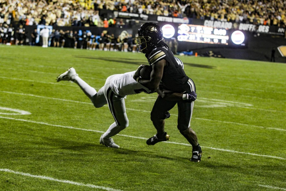 A Colorado receiver catches a pass and attempts to fight off a Kansas State defender.