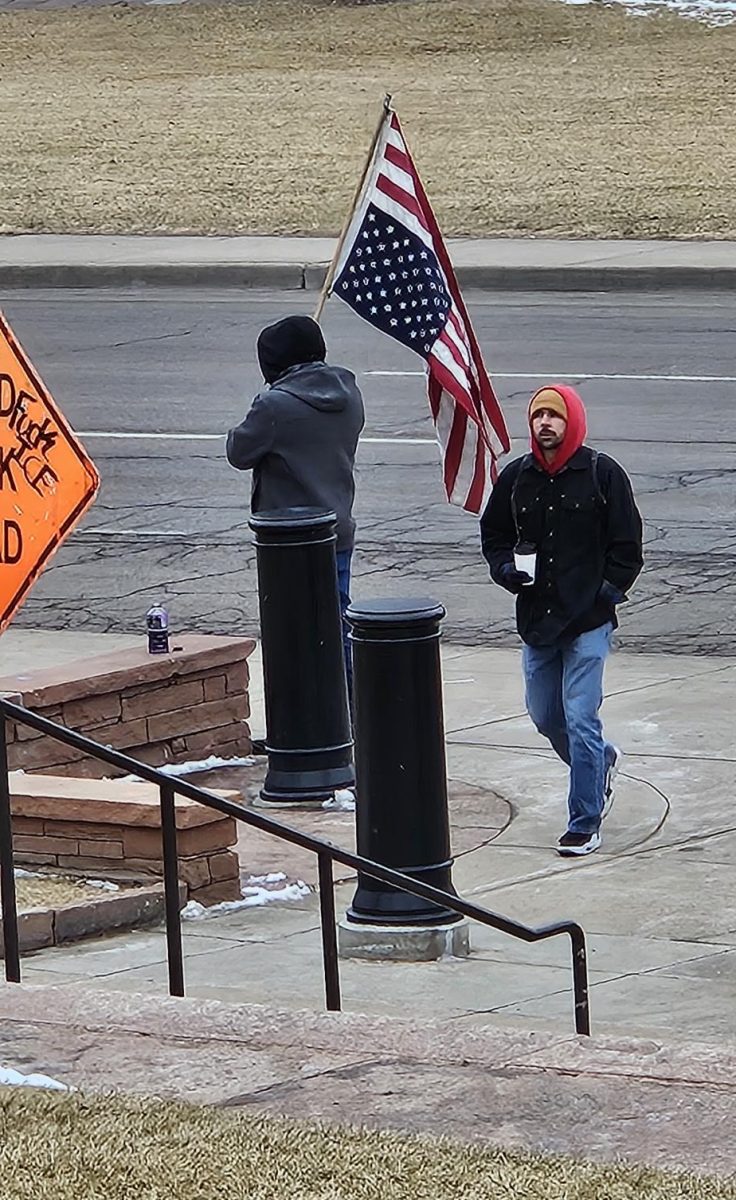 Protestor with upside down flag in front of Denver State Capital building