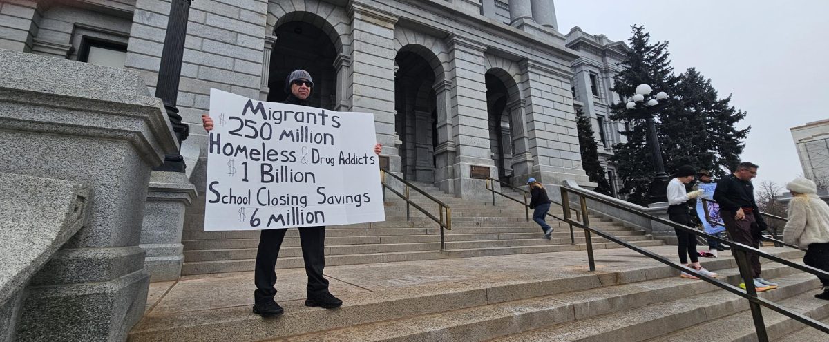 Protestor holding sign in front of Denver State Capital building