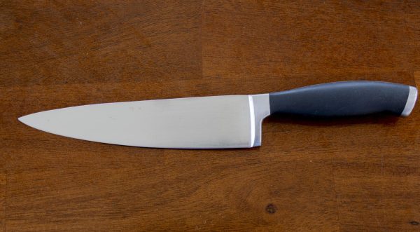 A chef's knife laid out on a table. 